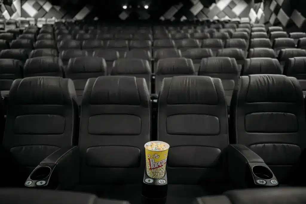 Vestíbulo de cine con carteles iluminados y múltiples pantallas de películas