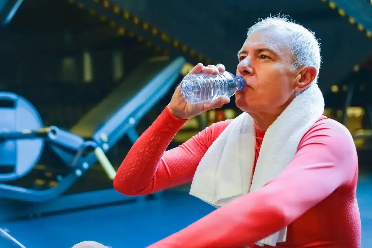 Persona mayor hidratándose durante el calor intenso del verano