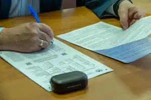 Mano firmando documento oficial en escritorio de despacho ministerial