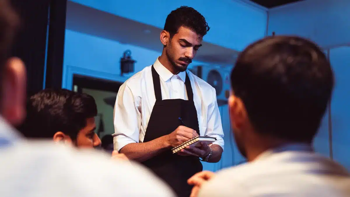 Camarero atendiendo mesas en un restaurante ocupado