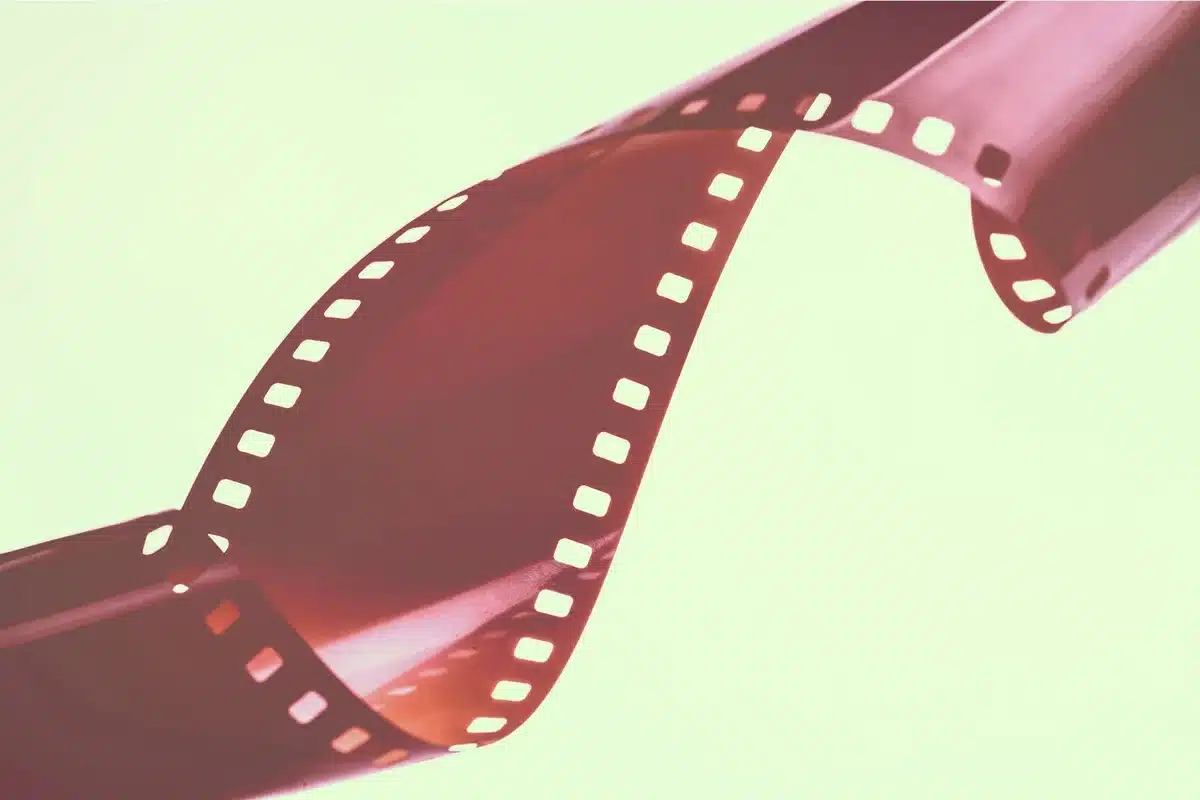 Bobinas de cine antiguas junto a dispositivo de streaming moderno, representando la evolución del cine