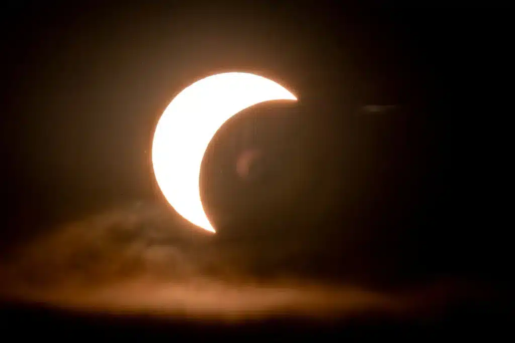 Observadores con telescopios bajo nubes de tormenta durante un eclipse solar