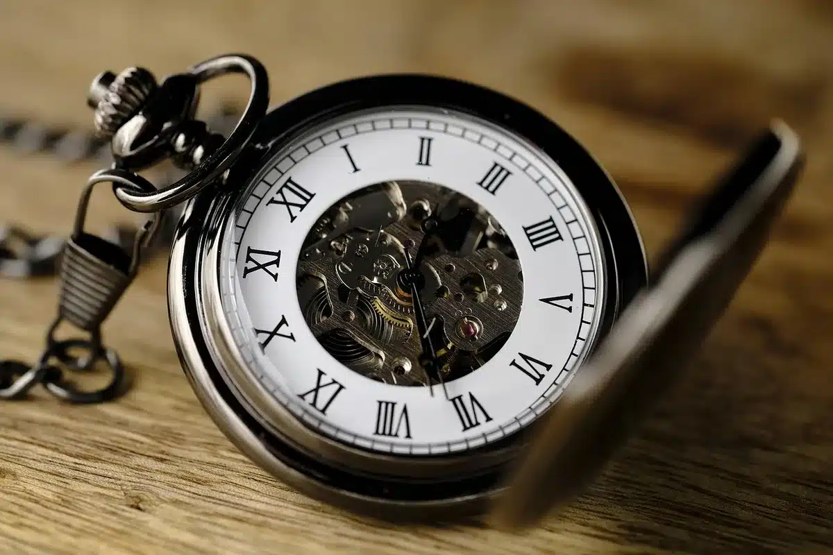 Reloj y manos trabajando parcialmente en una oficina