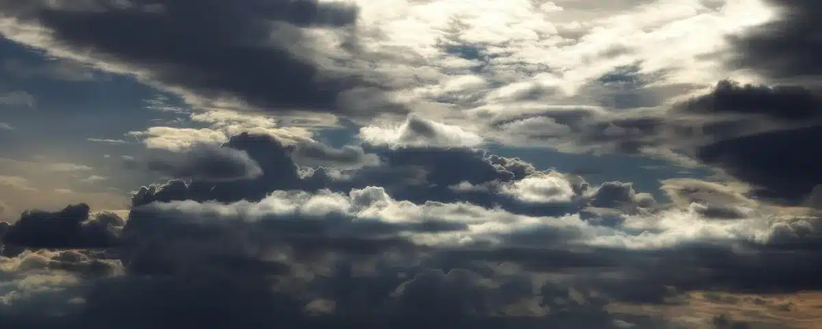 Promenade costera con gente anónima bajo paraguas y nubes de tormenta acercándose