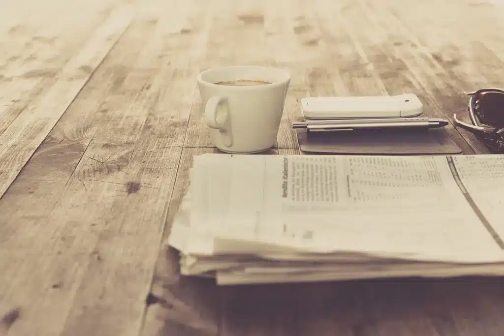 Manos leyendo un manuscrito sobre una mesa con una taza de café