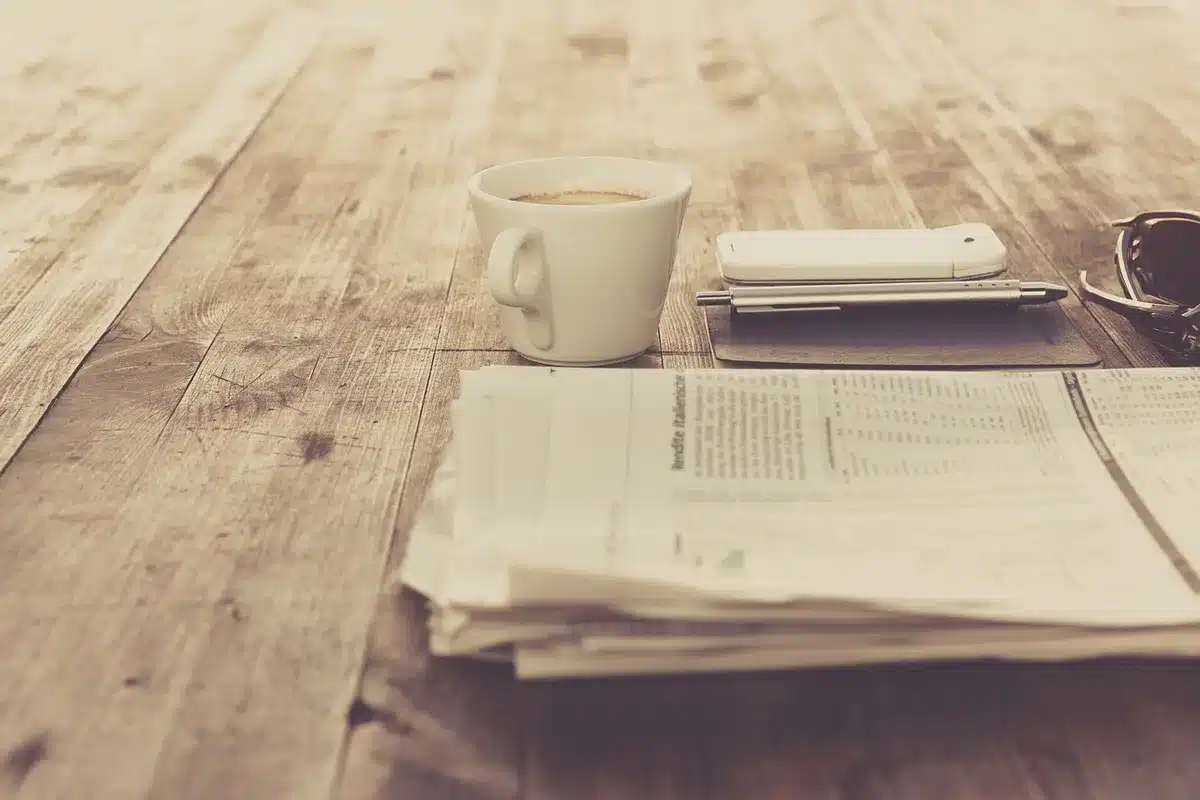 Manos leyendo un manuscrito sobre una mesa con una taza de café