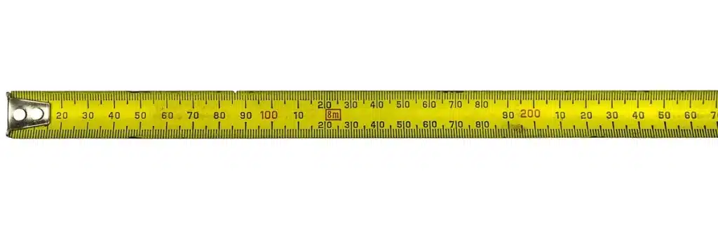 Manos anónimas de obrero con plano y cinta métrica en obra